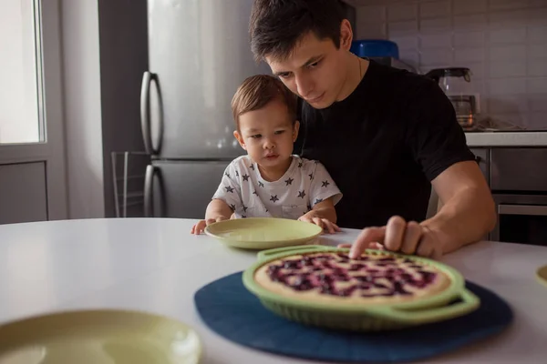 Padre e hijo en la cocina. niño quiere un delicioso pastel caliente . — Foto de Stock