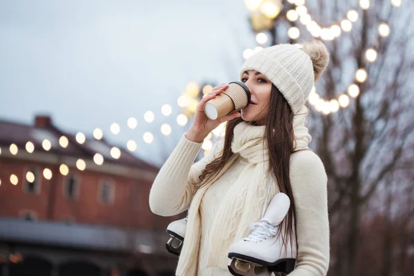 Joyeux jeune femme en pull tricoté et chapeau va patiner et boit du café — Photo