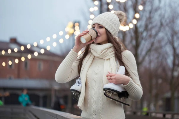 Joyeux jeune femme en pull tricoté et chapeau va patiner et boit du café — Photo