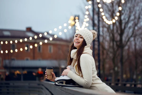 ニットのセーターと帽子で幸せな若い女スケートだし、コーヒーを飲む — ストック写真