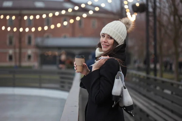 Jonge brunette met schaatsen op haar schouder, op een achtergrond van winter stad Park — Stockfoto
