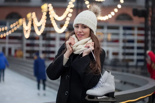 冬の都市公園の背景に、彼女の肩にスケートの若いブルネット — ストック写真