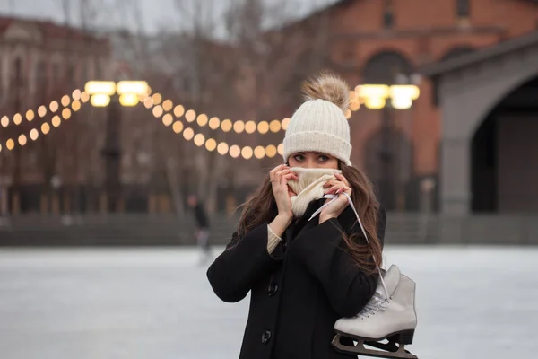 Jovem morena com patins no ombro, em um fundo de inverno cidade Park — Fotografia de Stock