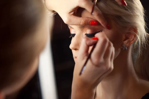 Beautiful young blonde. Makeup artist makes a stylish makeup. — Stock Photo, Image
