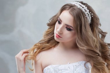 Lüks saç modeli ile büyüleyici genç gelin. Gelinlik güzel kadın. Kabarık kıvırcık saç modeli.