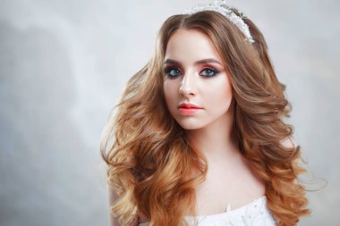 Lüks saç modeli ile büyüleyici genç gelin. Gelinlik güzel kadın. Kabarık kıvırcık saç modeli.