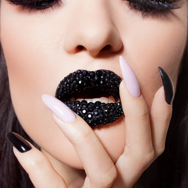 Lábios pretos cobertos de strass. Mulher bonita com batom preto em seus lábios e manicure preto e branco — Fotografia de Stock