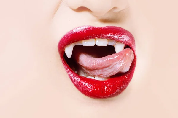 Vampiro sexy. Labios de mujer con lápiz labial rojo. Lengua lamiendo colmillos vampiro — Foto de Stock