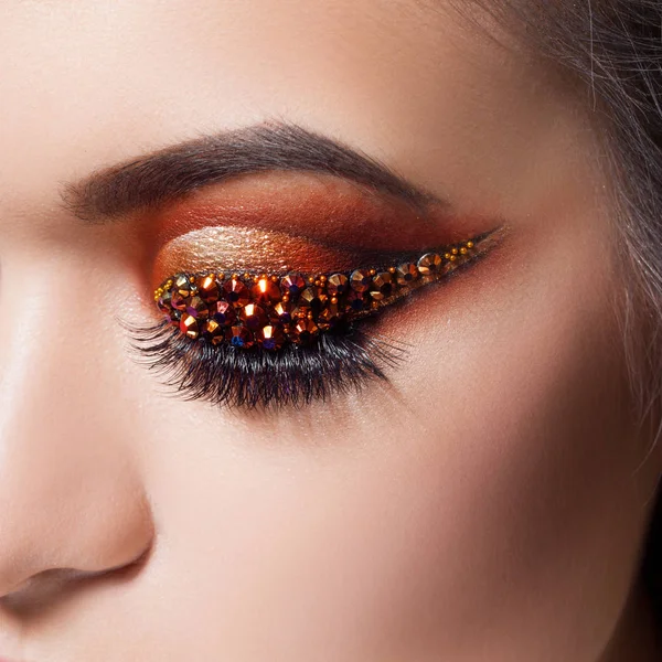 Amazing Bright eye makeup with a arrow with rhinestones. Brown and gold tones, colored eyeshadow — Stock Photo, Image
