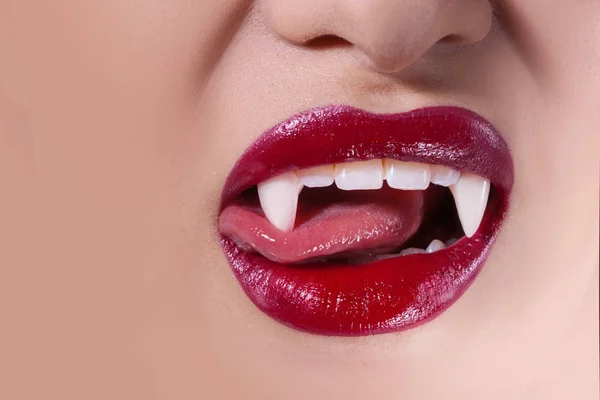 Vampiro sexy. Labios de mujer con lápiz labial rojo. Lengua lamiendo colmillos vampiro —  Fotos de Stock