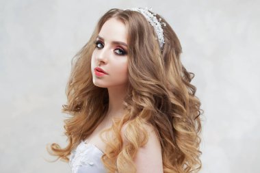 Lüks saç modeli ile büyüleyici genç gelin. Gelinlik güzel kadın. Kabarık kıvırcık saç modeli.