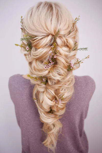 Vista posterior de un elegante peinado de moda, entrelazando rizos y decorando con pétalos de flores — Foto de Stock