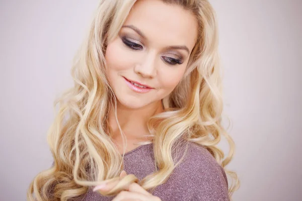 Porträt einer schönen blonden jungen Frau mit langen luxuriösen Locken. — Stockfoto