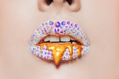 dudaklar parlayan rhinestones ve altın lekeleri ile kaplı. Dudaklarında beyaz ruj ile güzel kadın
