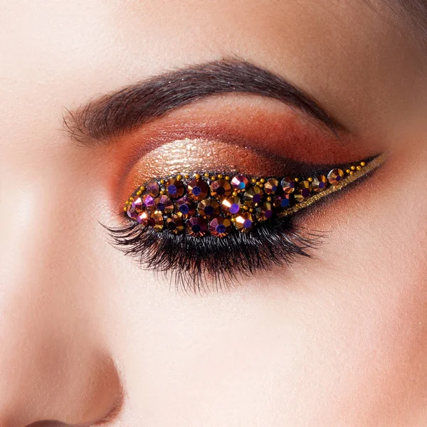 Amazing Bright eye makeup with a arrow with rhinestones. Brown and gold tones, colored eyeshadow — Stock Photo, Image