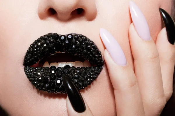 Lábios pretos cobertos de strass. Mulher bonita com batom preto em seus lábios e manicure preto e branco — Fotografia de Stock