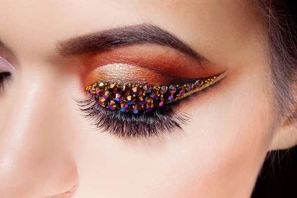 Verbazend helder oog make-up met een pijl met strass. Bruin en gouden tinten, gekleurde oogschaduw — Stockfoto