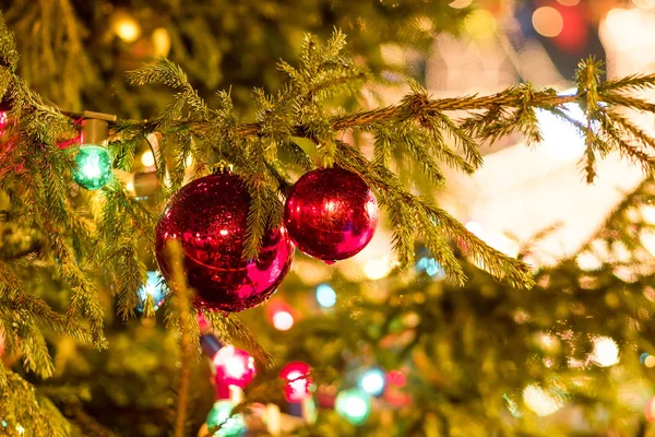 Due palline rosso lucido sull'albero. Capodanno decorazioni stradali, decorazioni natalizie e ghirlande — Foto Stock