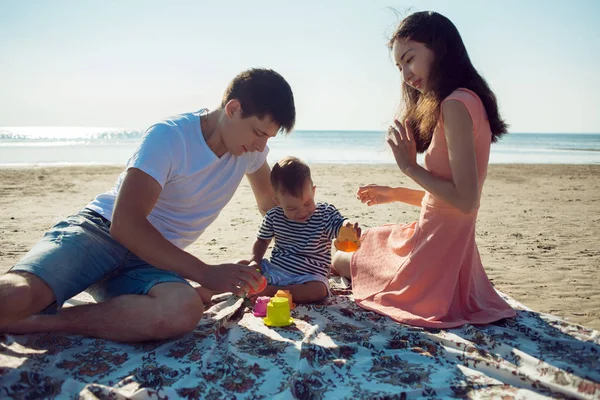 La famiglia multietnica allegra ha un riposo su una riva di mare . — Foto Stock