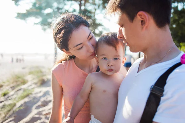 Retrato de familia joven y feliz con un bebé encantador. Picnic en la playa — Foto de Stock