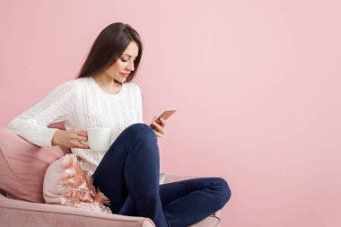 Sevimli genç esmer bir sandalyede oturuyor ve bir akıllı telefon sohbet