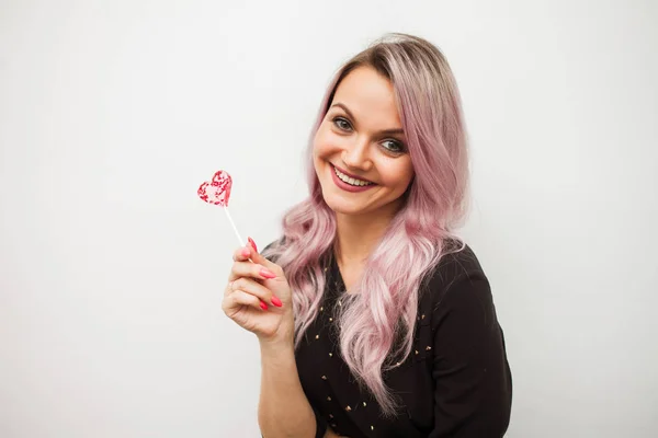 Lovely чарівна дівчина з льодяник у вигляді серця. Портрет молодої жінки з рожевим волоссям і рожевий цукерки — стокове фото