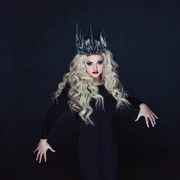 Retrato de uma princesa gótica. Mulher loira jovem bonita em coroa de metal e capa preta . — Fotografia de Stock