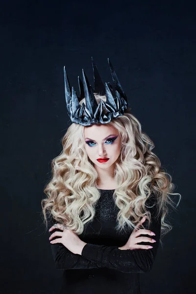 Portrait of a Gothic Princess. Beautiful young blonde woman in metal crown and black cloak.