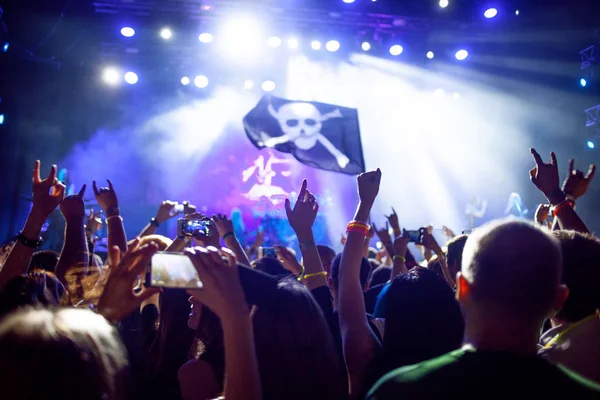 Concierto de rock, las manos arriba. La gente es feliz en el club, bandera pirata delante de las luces — Foto de Stock