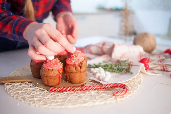 Girl decorates New Year celebration cupcakes, chocolate muffins on table — Stock Photo, Image