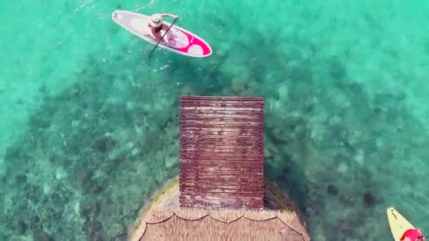 A rapariga do SUP Board nada perto do cais. A mais pura água azul-turquesa. Paraíso natureza em uma ilha tropical — Vídeo de Stock