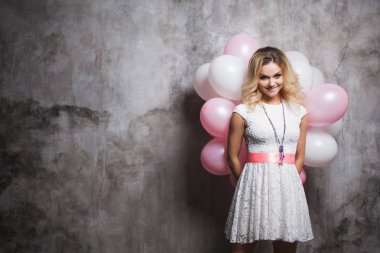 Pembe balloonsbehind arka ile beyaz elbiseli çekici genç sarışın. Balonlar ile mutlu ve neşeli kız.