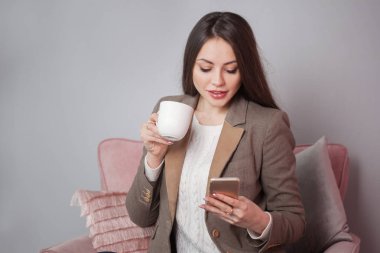 Büyüleyici iş esmer bir sandalyede oturuyor ve bir akıllı telefon sohbet ceketli