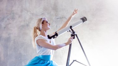 Genç kadın gelecek, kavram hayalleri. Bulutlar gökyüzü kız baktı ve bir teleskop kullanır.