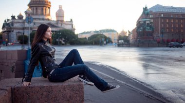 Kot pantolon kentin turistik St. Petersburg arka plan üzerinde oturan kız. 