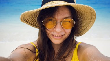 Mutlu kız tatilde. Genç esmer bir selfie alarak bir hasır şapka ve güneş gözlüğü,