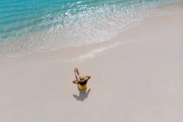 Girl alone on seashore and enjoys the sun. Young woman in a straw hat and yellow swimsuit — Stock Photo, Image