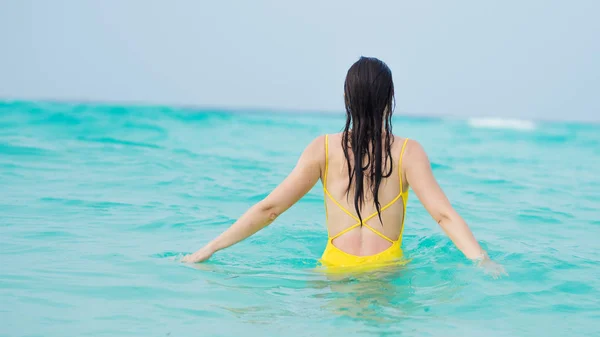 Young brunette woman in yellow one piece swimsuit. — Stock Photo, Image
