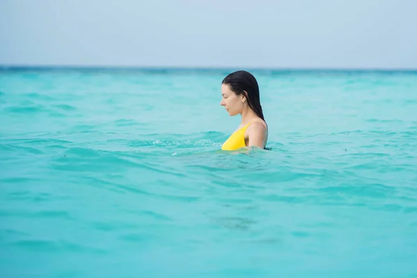 Young brunette woman in yellow one piece swimsuit. — Stock Photo, Image