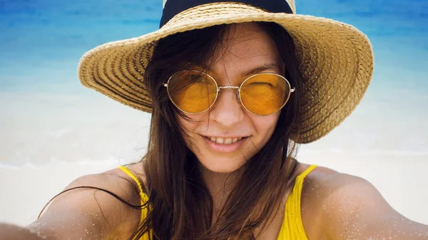 Chica feliz de vacaciones. Joven morena con sombrero de paja y gafas de sol, tomando una selfie —  Fotos de Stock
