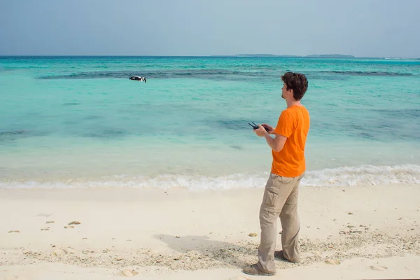 Guy launches a drone over the sea, photo and video shooting on quadrocopter — Stock Photo, Image