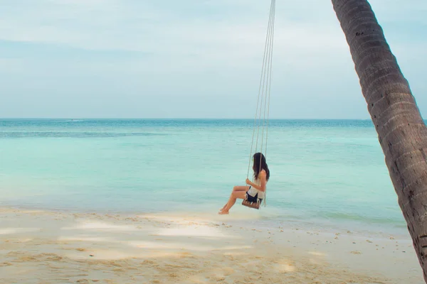 Swing on a palm tree. Beautiful island landscape with relaxing girl on a swing. — Stock Photo, Image