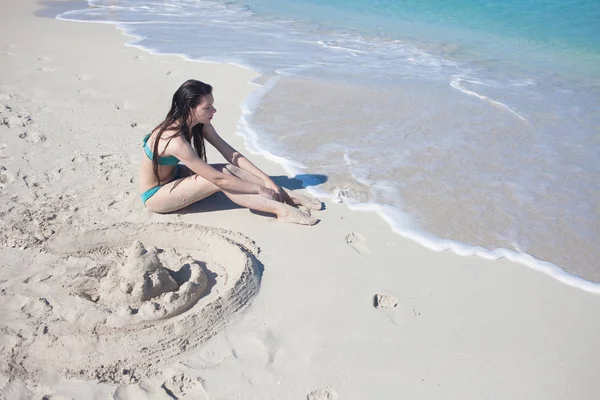 Jovem na praia construiu um castelo de areia . — Fotografia de Stock