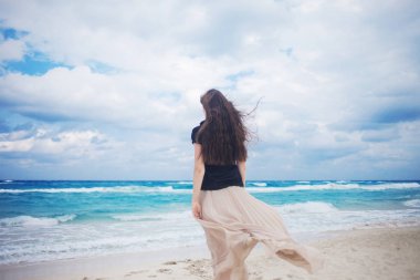 Okyanusta yürümeye uzun etekli genç kadın arkadan görünüm. 