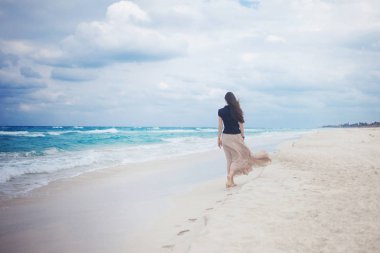 okyanusta yürümeye uzun etekli genç kadın. 