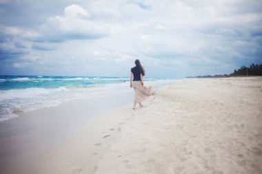 okyanusta yürümeye uzun etekli genç kadın. 