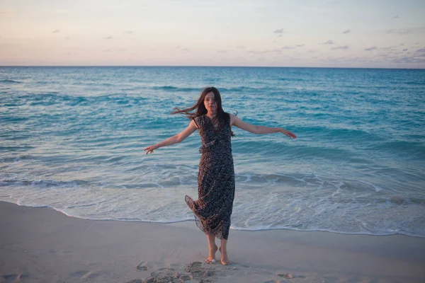 Jonge vrouw in een lange jurk lopen op de Oceaan. — Stockfoto