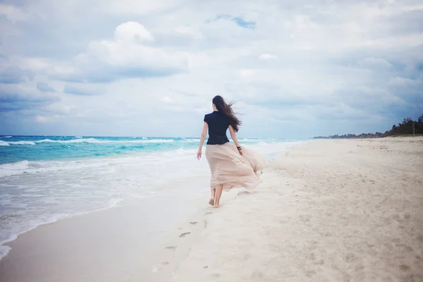 Jonge vrouw in een lange rok die lopen op de Oceaan. — Stockfoto