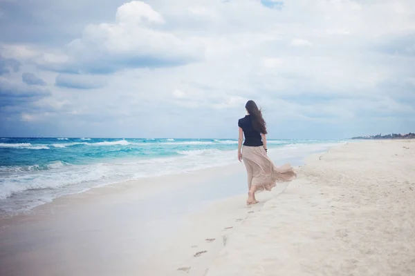 Jonge vrouw in een lange rok die lopen op de Oceaan. — Stockfoto