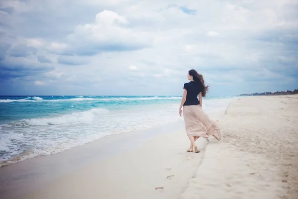 Ung kvinna i en lång kjol walking på havet. — Stockfoto